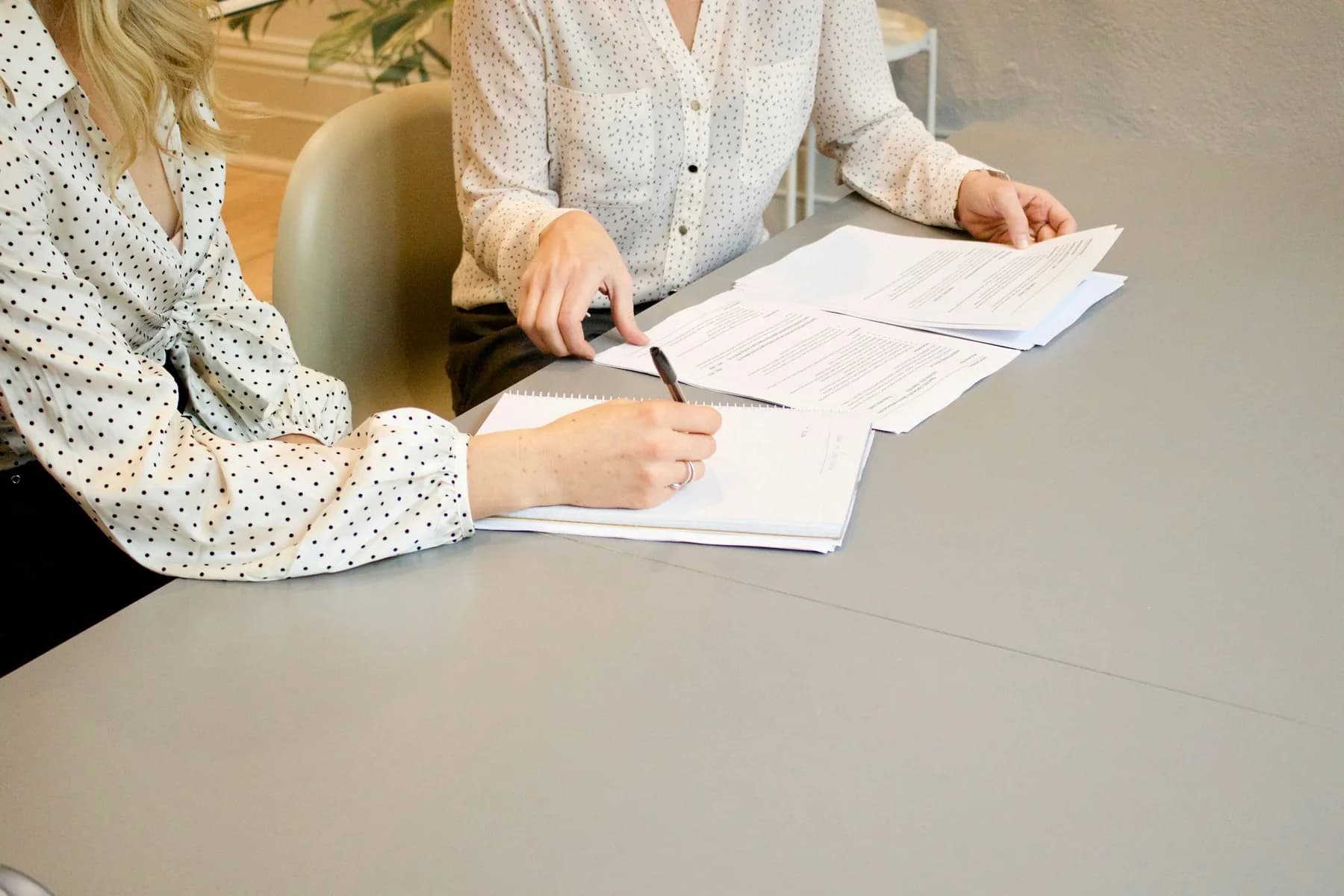 Two professionals reviewing printed documents at a conference table.